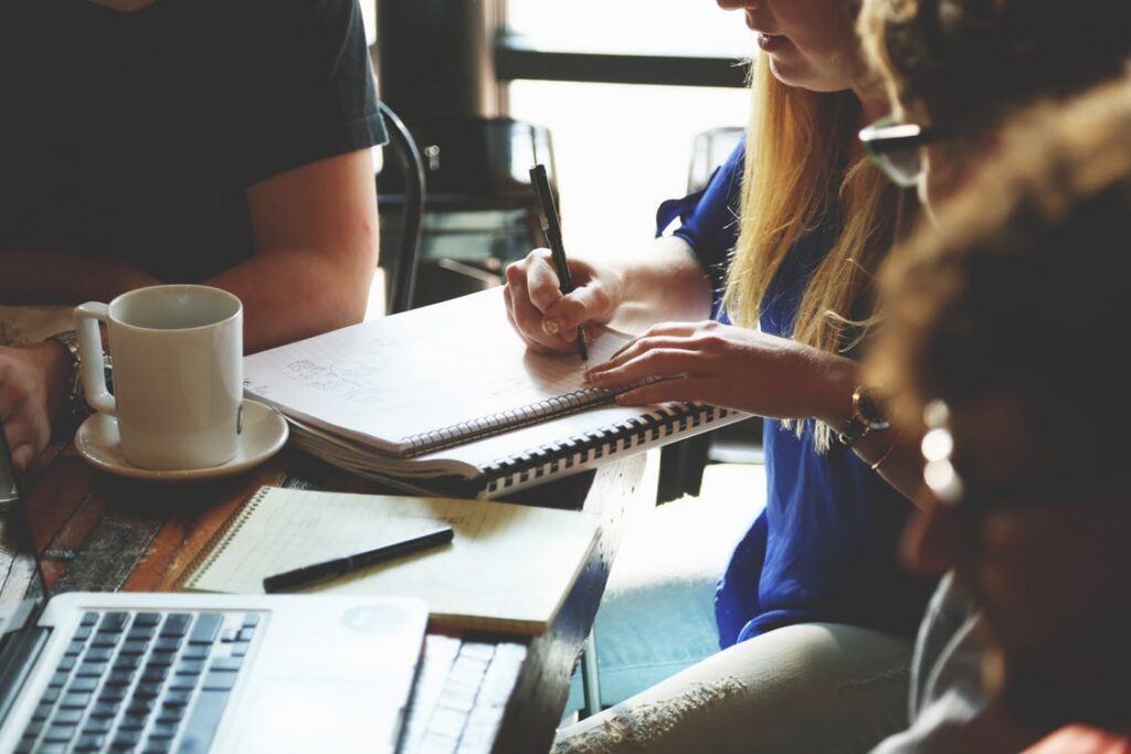 People in a coffee meeting; a woman taking down notes